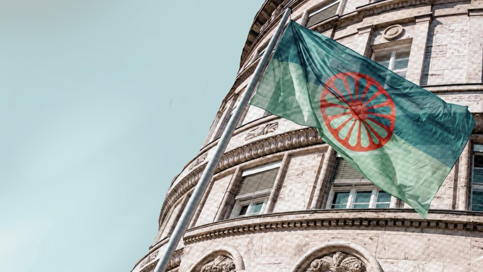 Flag of the Romani people flying in front of an official looking building